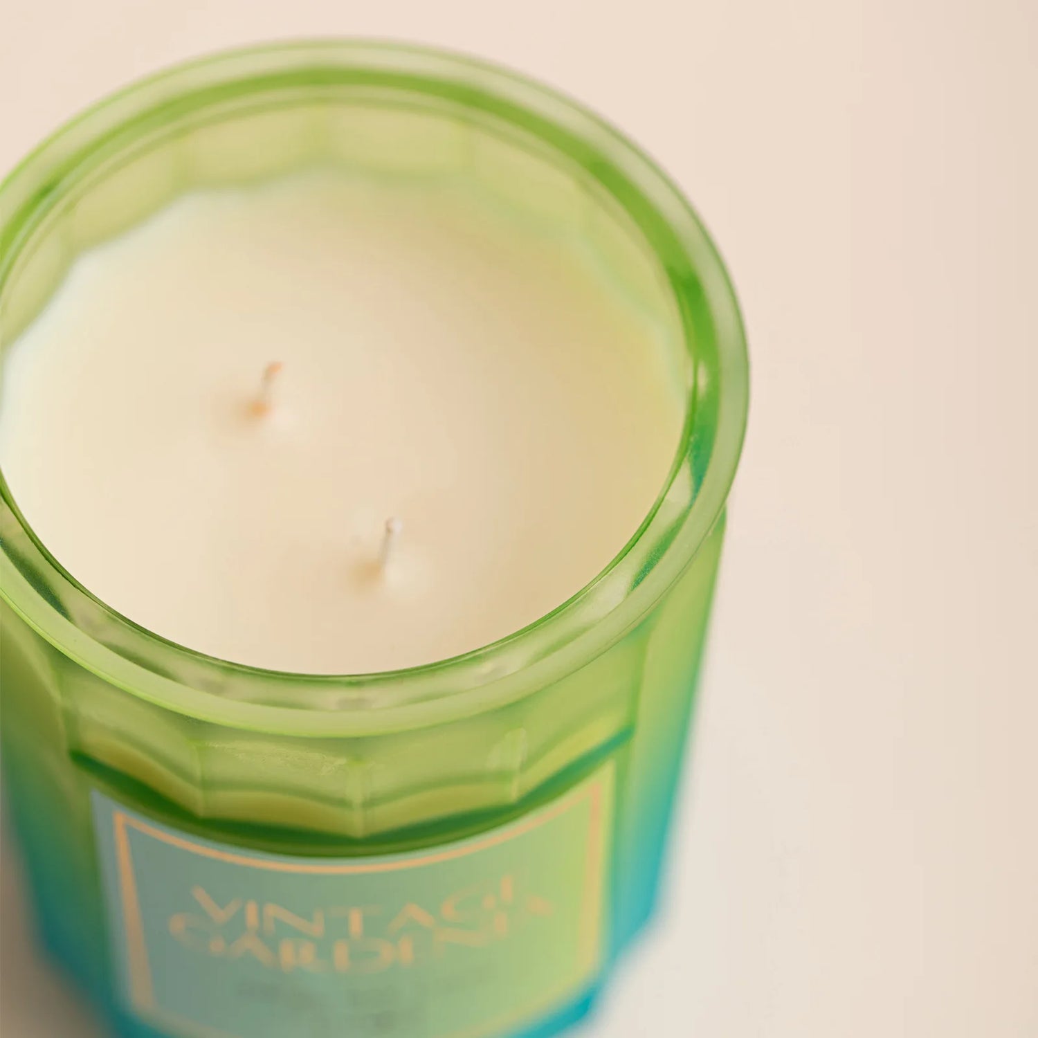 Une bougie naturelle dans un récipient en verre teinté de vert, dégageant une douce lumière.