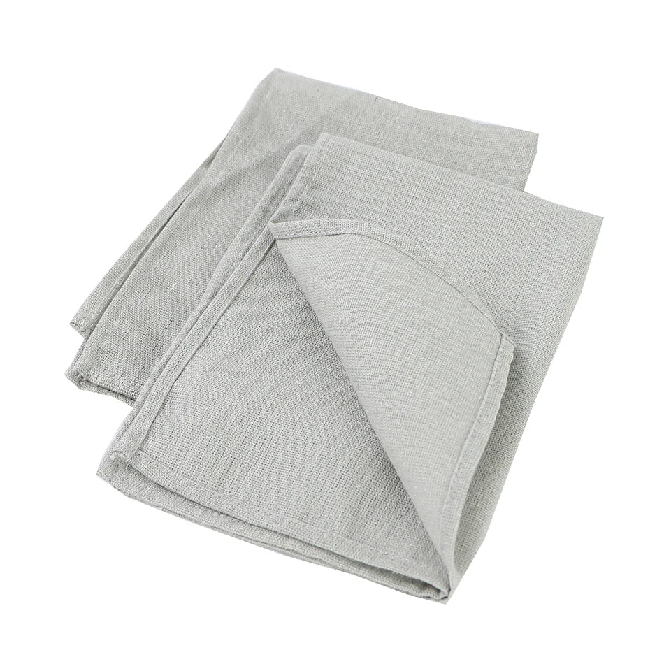 Serviettes de cuisine en lin gris, pliées et posées sur un fond blanc.
