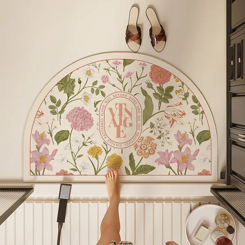 Cette image montre un panneau ornemental avec un motif floral entourant le monogramme "Xya", placé sur un mur avec des accessoires de décoration, notamment des sandales et un appareil électronique.