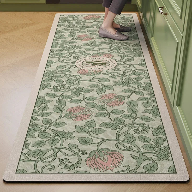 Un tapis décoratif à motifs floraux et végétaux dans des tons verts et roses, posé sur un sol en bois clair.