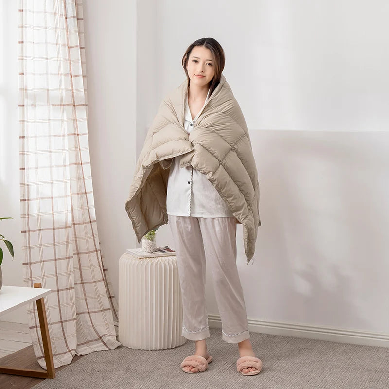 Une femme vêtue de vêtements décontractés se tient debout dans une pièce lumineuse, enveloppée dans une couverture confortable.