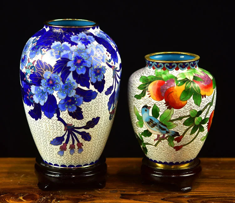 Deux vases en céramique colorés ornés de motifs floraux et de scènes de la nature sur un fond sombre.