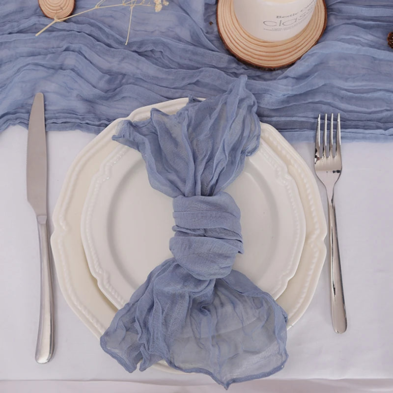 Un élégant service de table en blanc et bleu, avec des détails raffinés comme un pli de tissu gris et des couverts en métal.