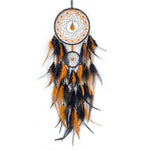 Capteur de rêves suspendu avec motif en filet, plumes noires et orange, et ornements, créant une décoration murale unique et ethnique.