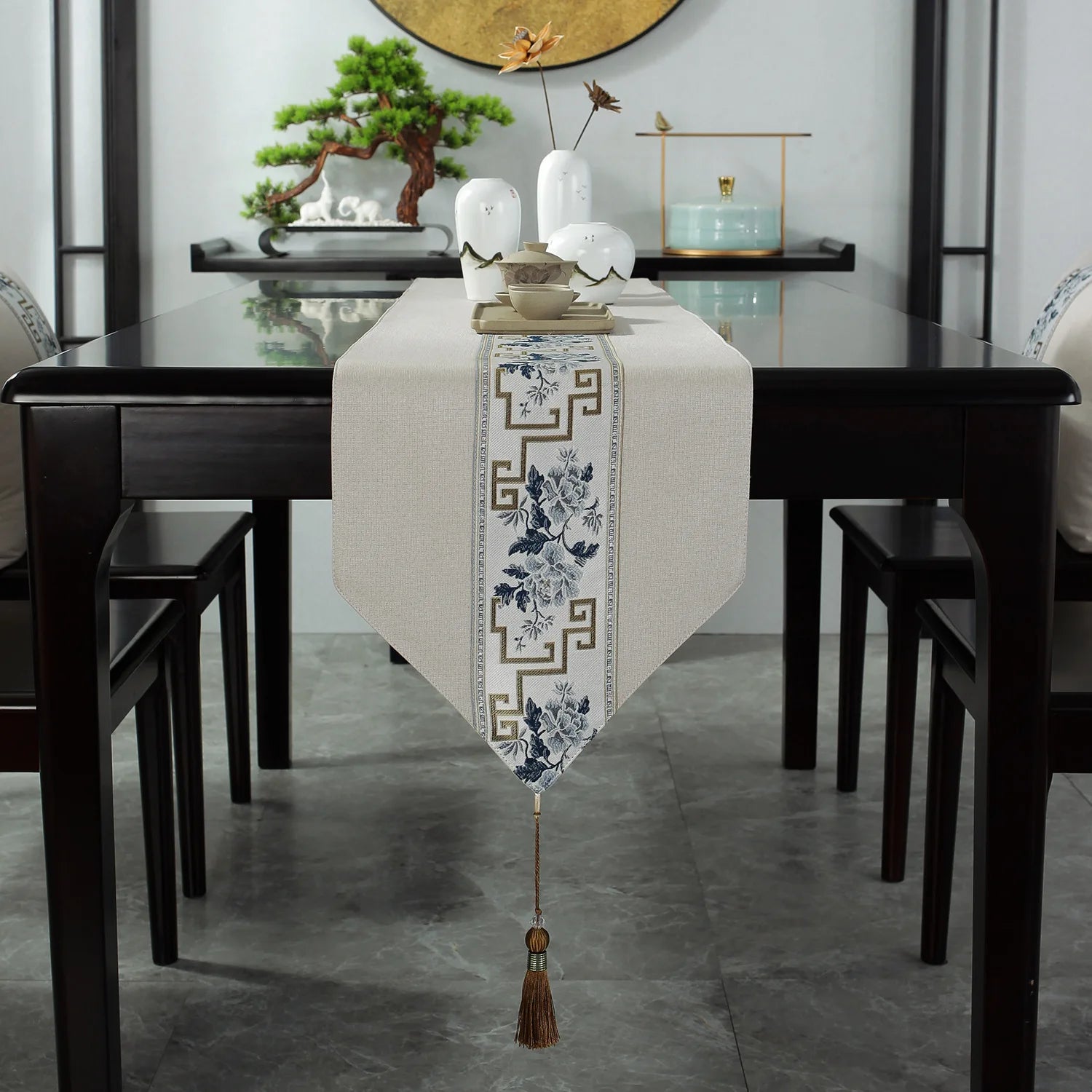 Une élégante table de salle à manger avec un chemin de table décoratif, un bonsaï et des accessoires de style asiatique.