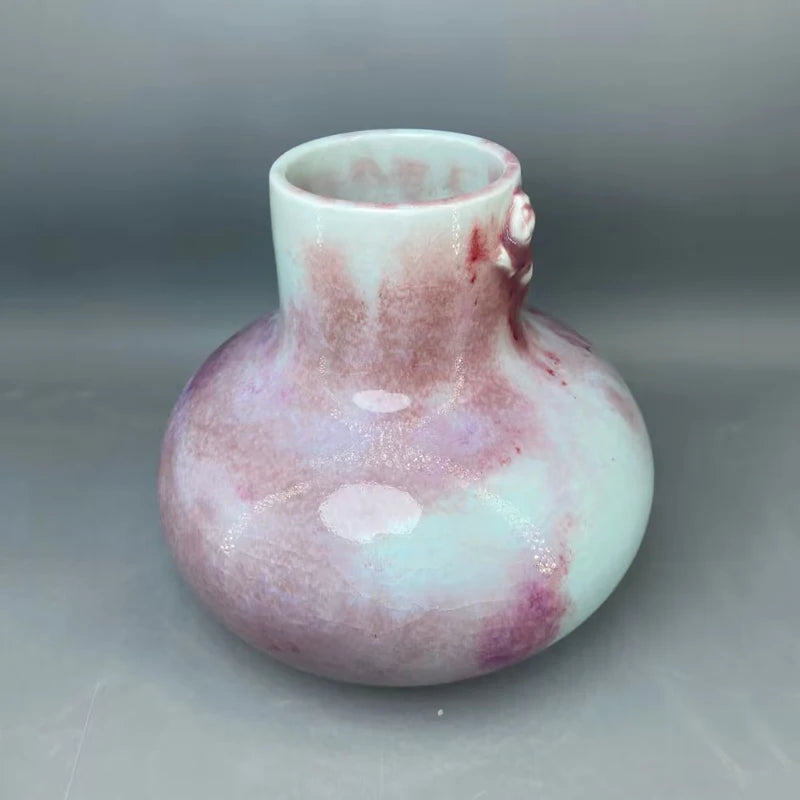 Un vase en verre coloré aux teintes rose et menthe, aux formes arrondies et irrégulières, créant un effet esthétique unique et harmonieux.