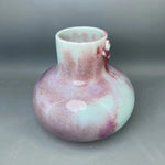 Un vase en verre coloré aux teintes rose et menthe, aux formes arrondies et irrégulières, créant un effet esthétique unique et harmonieux.