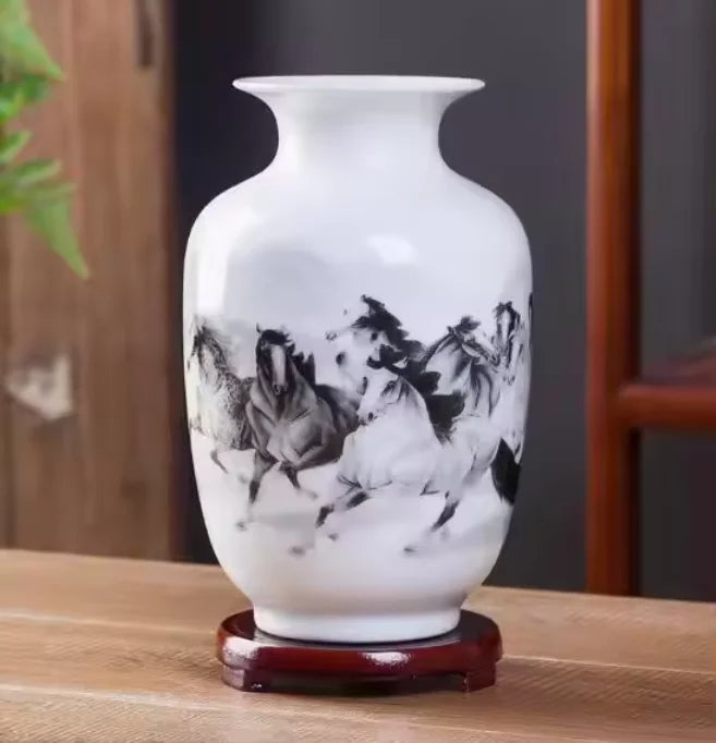 Un vase décoratif blanc avec une magnifique gravure en noir et blanc représentant des chevaux au galop dans un paysage naturel.