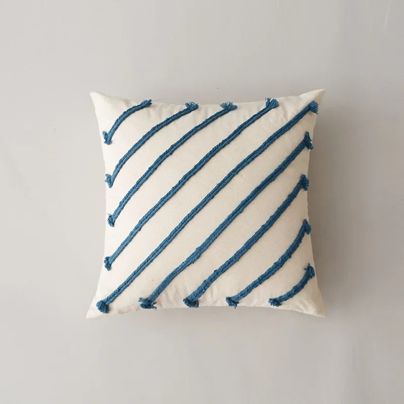 Coussin blanc décoratif avec des lignes diagonales bleues tissées.