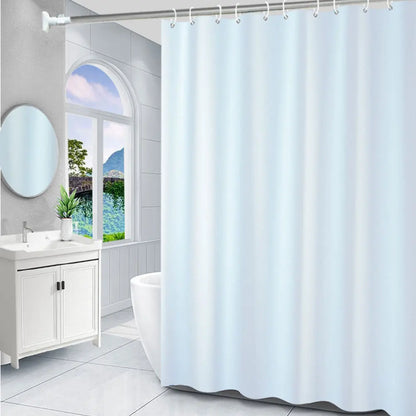 Salle de bain blanche et épurée, agrémentée d’un rideau de douche uni aux tons très clairs devant une large fenêtre offrant une vue sur un paysage.