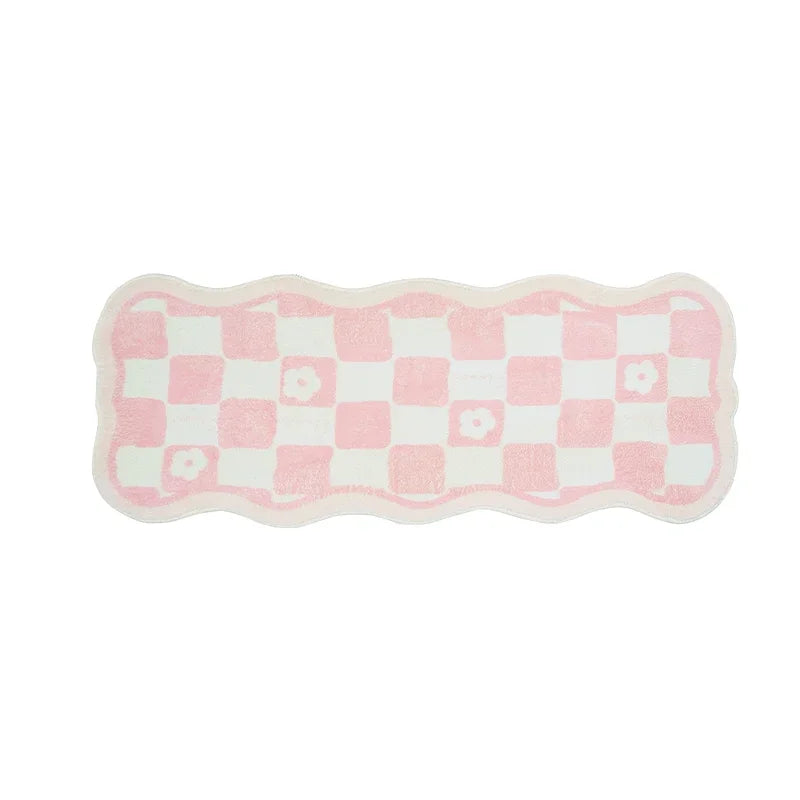 Tapis de salle de bain en forme ondulée avec motif de carrés roses et blancs.