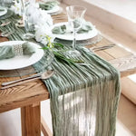 serviette table vert plissée moderne assiettes blanches verres vin bougies vase blanc pompons blancs