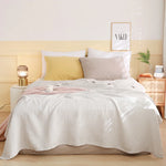 Chambre cosy aux tons pastel, avec un lit douillet, des coussins moelleux et un cadre décoratif sur le mur.
