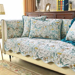 Le canapé est couvert d'un joli motif floral aux couleurs vives, créant une ambiance chaleureuse et relaxante dans la pièce.