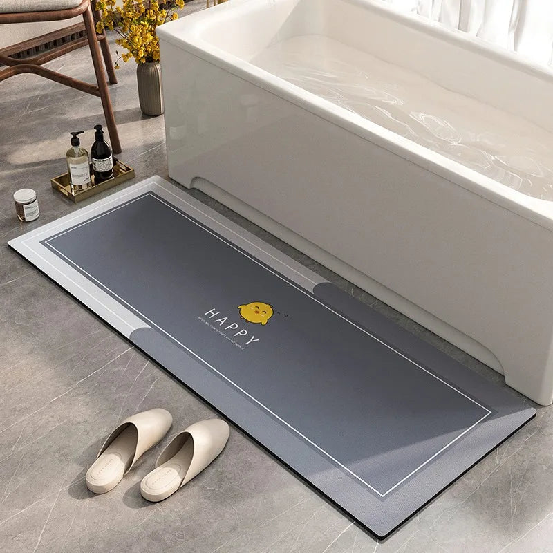 Un tapis de bain antidérapant gris orné d'un logo jaune "Happy" est posé près d'un bain blanc, complétant l'ambiance relaxante de cette salle de bain.