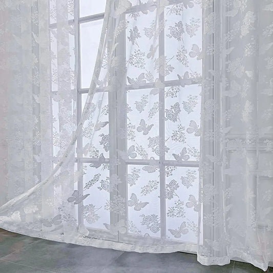 Voilage blanc transparent à motifs papillons et fleurs vu en gros plan dans une pièce lumineuse.
