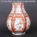 Cette image montre un vase décoratif en céramique de style traditionnel chinois, avec des motifs floraux et des scènes naturelles peints en couleurs vives sur un fond blanc et rouge.
