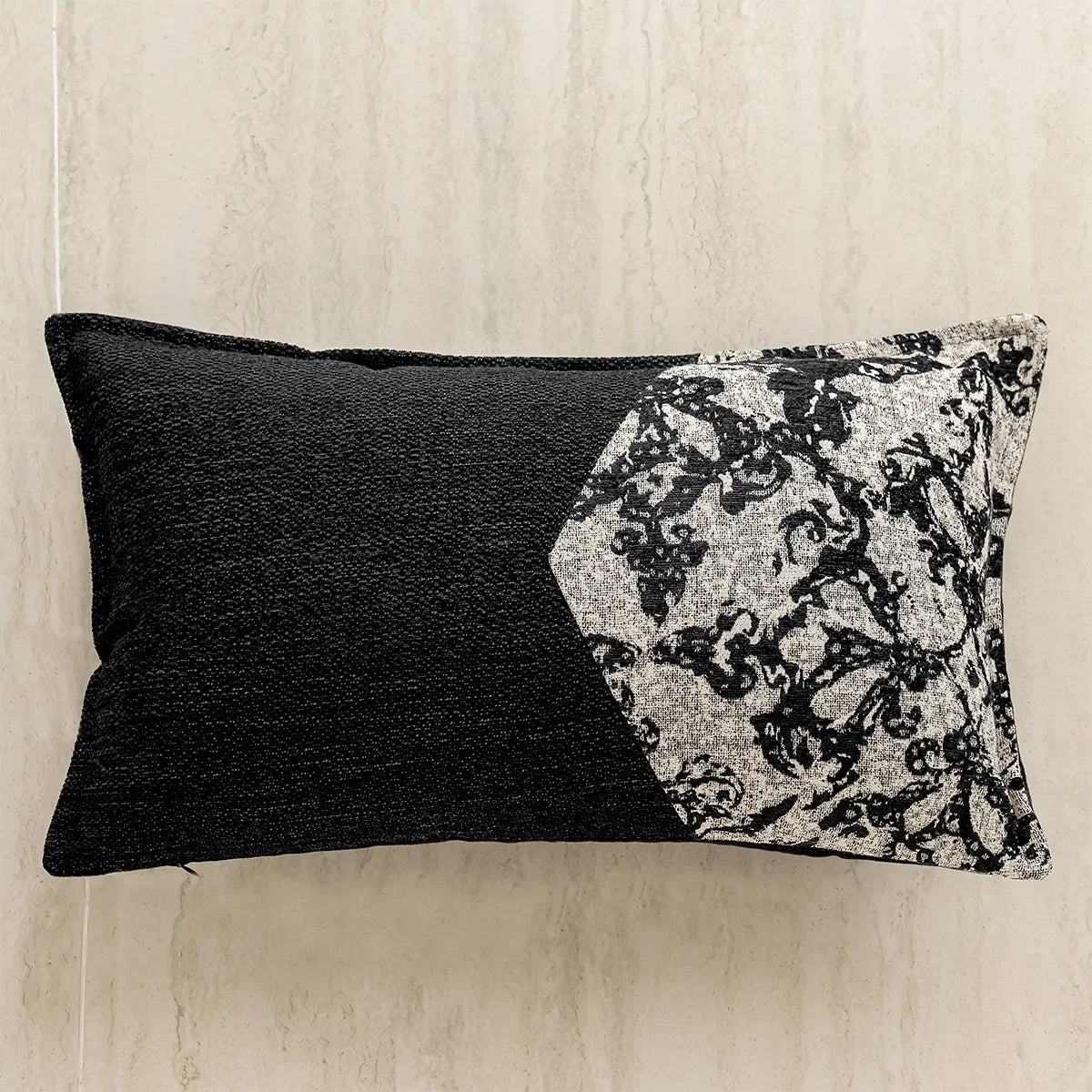 Un coussin décoratif avec un design géométrique abstrait en noir et blanc, créant un contraste saisissant sur un fond texturé.