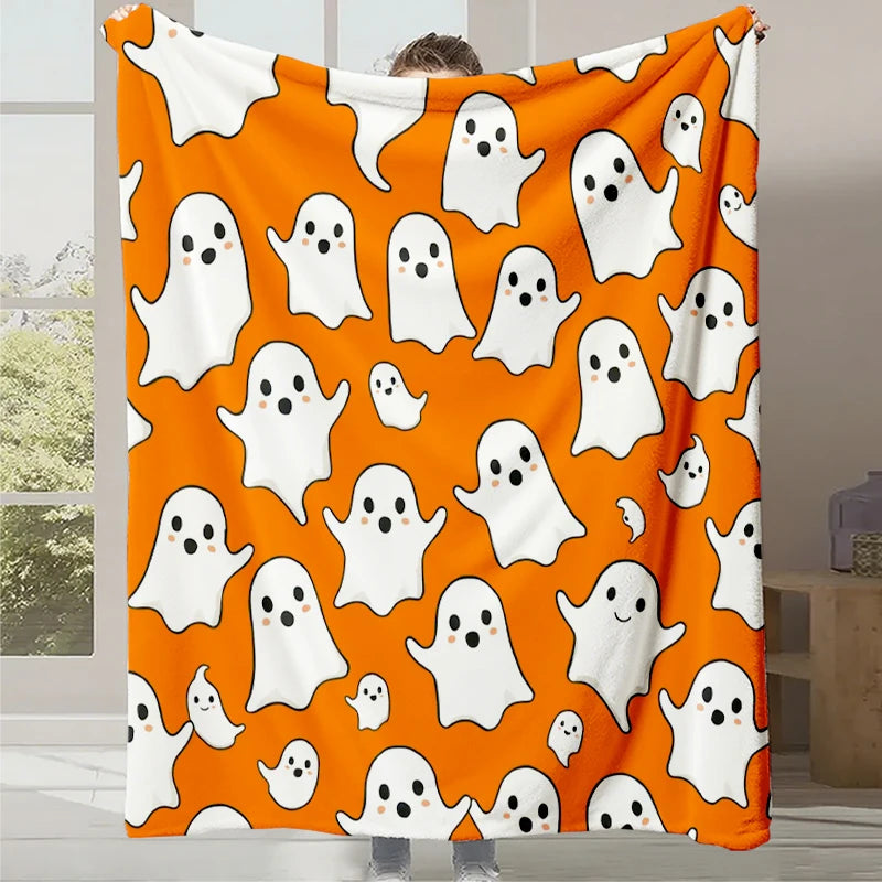 Une couverture orange avec des fantômes blancs souriants imprimée sur le tissu.