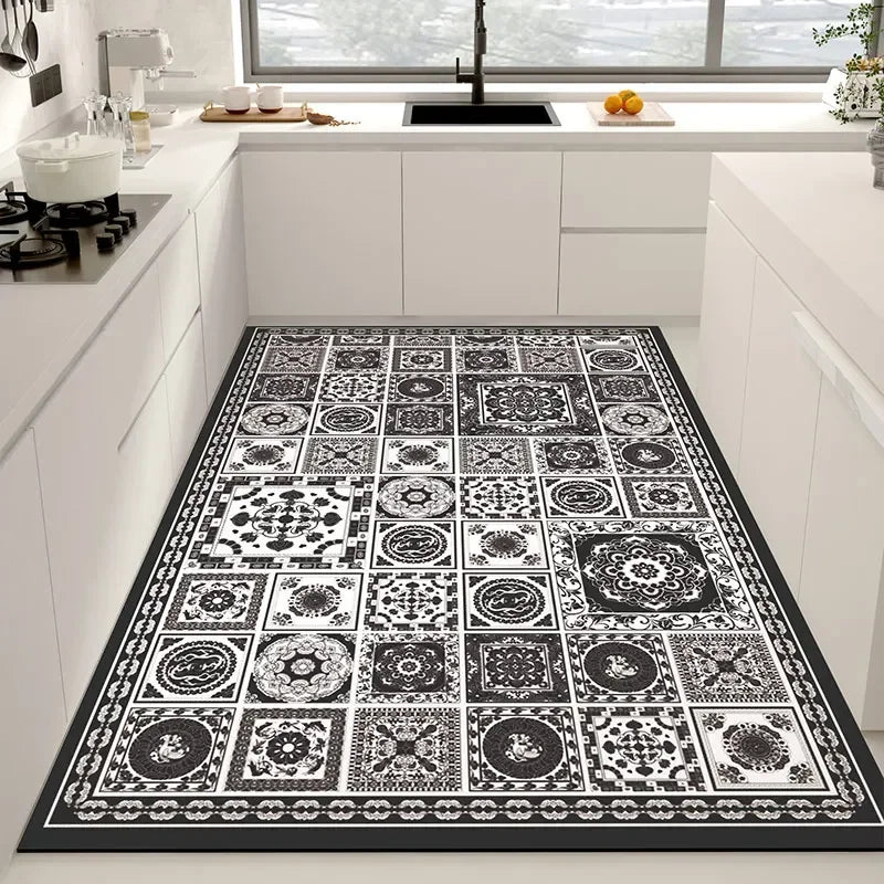 Tapis décoratif en noir et blanc avec des motifs ornementaux géométriques et floraux sur un sol de cuisine moderne avec des armoires blanches.