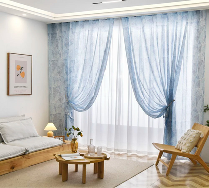 Zoom sur le voilage géométrique bleu translucide posé dans un coin cosy de salon.
