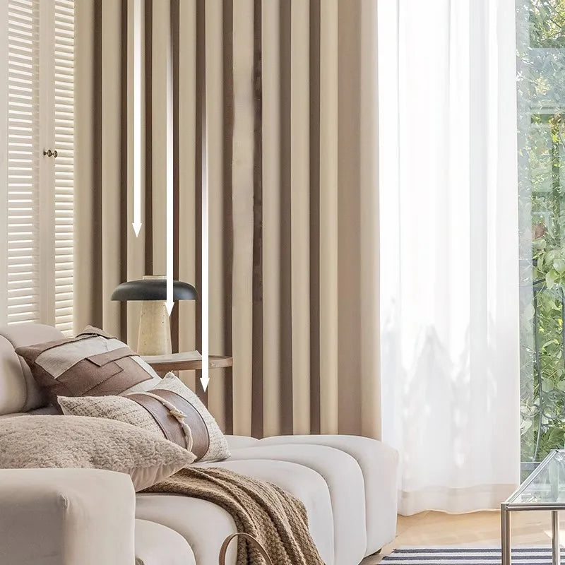 Rideau isolant beige dans un salon lumineux avec canapé crème, coussins texturés et lumière naturelle filtrée à travers un voilage blanc.