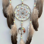 Superbe décoration murale artisanale composée d'un capteur de rêves en macramé orné de perles, de plumes et d'un pendentif en forme d'arbre de vie multicolore, suspendu à des branches de fourrure.