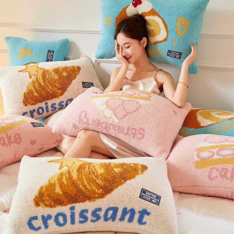 Une femme souriante enveloppée dans des coussins et couvertures imprimés de croissants colorés, suggérant une scène confortable et apaisante.