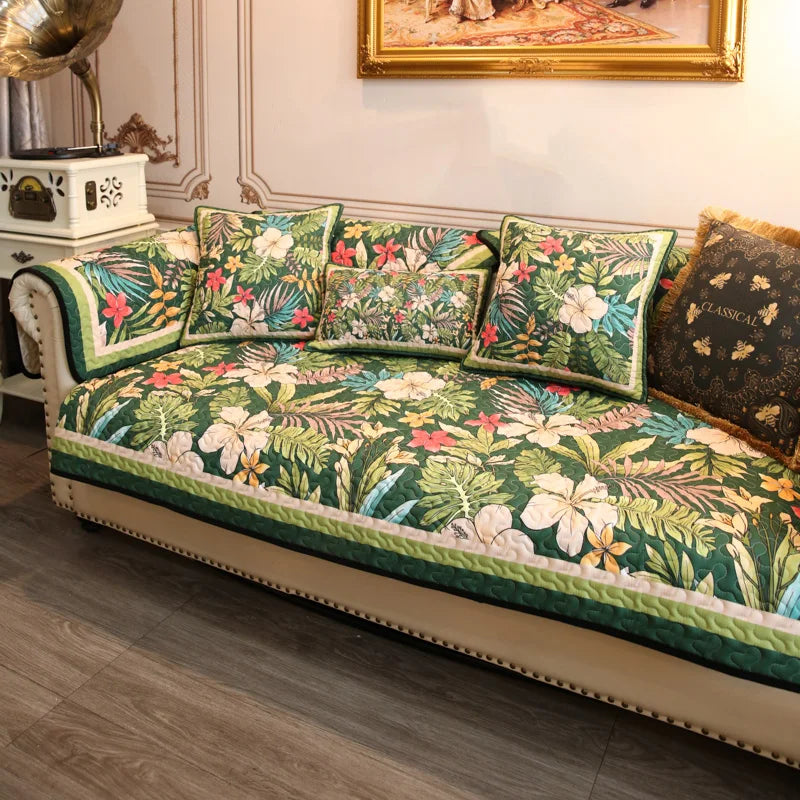 Un canapé recouvert d'un motif tropical coloré, composé de feuilles vertes, de fleurs rouges et de détails dorés, créant une ambiance chaleureuse et exotique dans la pièce.