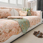 Un intérieur lumineux et cosy avec un canapé moelleux recouvert de motifs floraux aux teintes douces, une décoration chaleureuse et apaisante.