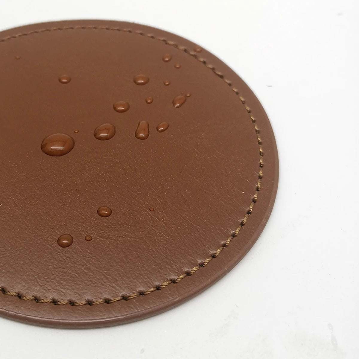 Gros plan d'un plateau rond en cuir brun, décoré de points sombres et de bordures tressées, suggérant une texture et une finition artisanales.