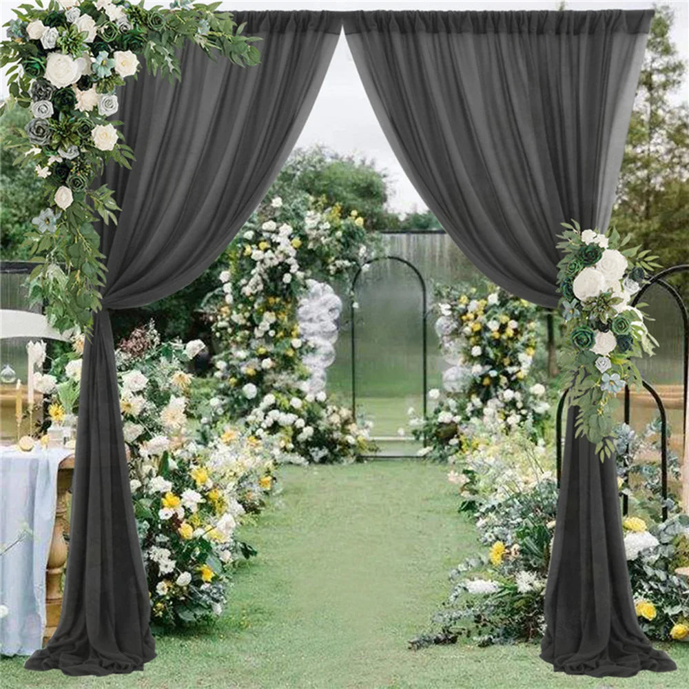 Un magnifique décor de mariage en plein air, avec un chemin fleuri entouré de rideaux gris et de compositions florales luxuriantes.