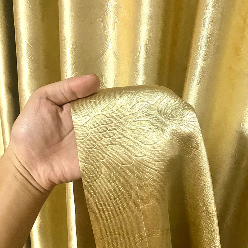 Détail de la texture du rideau doré avec une main tenant un ruban assorti, montrant la qualité et l’épaisseur du tissu.