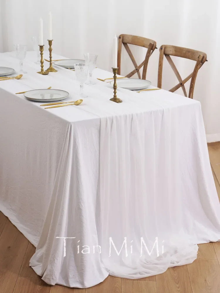 Une belle table dressée de manière élégante, avec des chandeliers dorés et des couverts sur une nappe blanche immaculée.