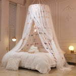 Une chambre élégante et féminine avec un lit confortable sous un baldaquin décoré de motifs colorés, créant une atmosphère douce et chaleureuse.