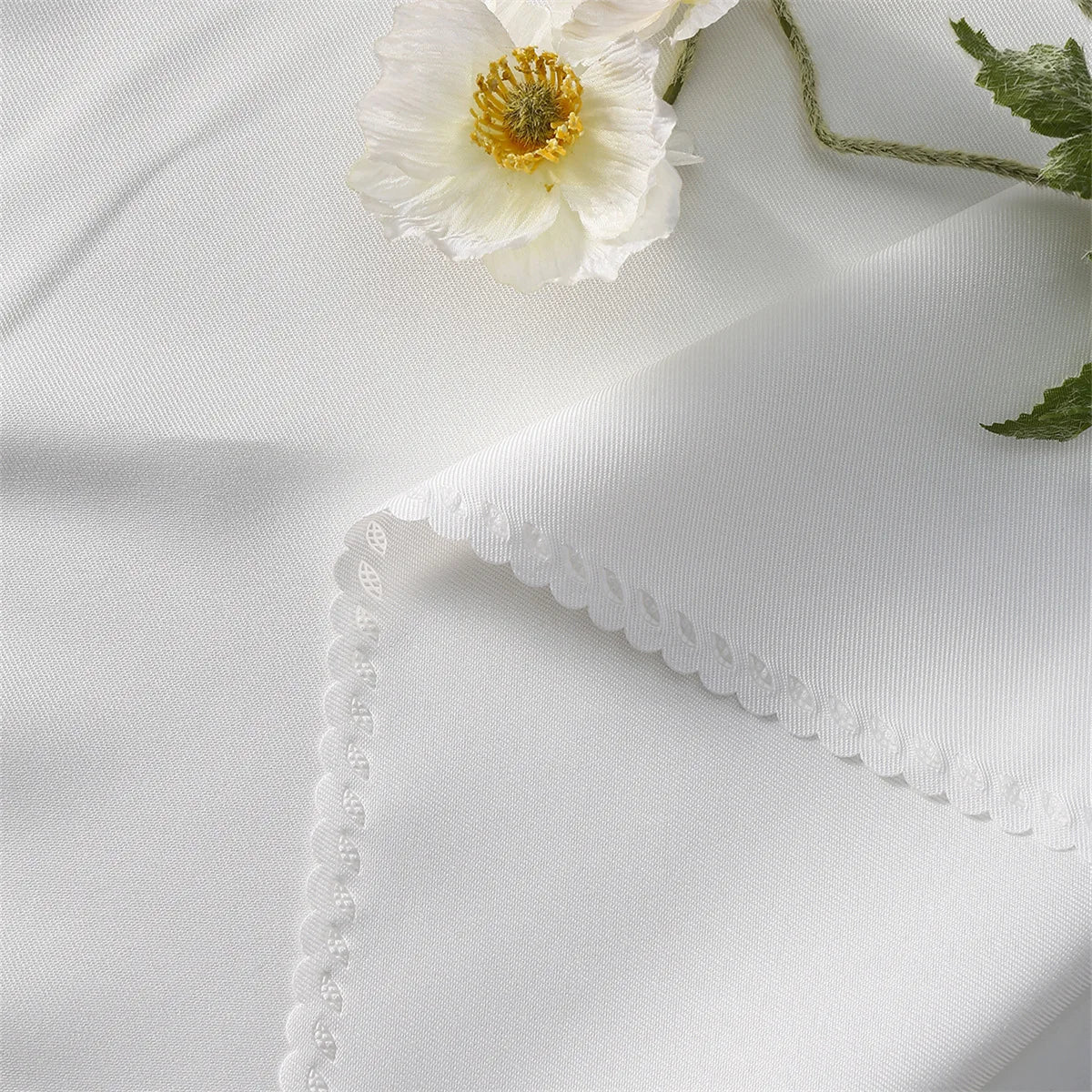 Une délicate fleur blanche sur un fond de tissu texturé.