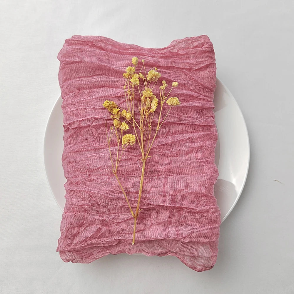 Une délicate branche de fleurs jaunes éparpillées sur un tissus plissé de couleur rose pâle.