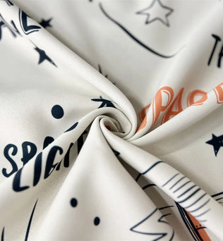 Tissu décoratif blanc avec motifs cosmiques et inscriptions stylisées en lettres noires et oranges, idéal pour les projets de couture modernes et créatifs. Parfait pour donner une touche d'originalité à votre intérieur ou pour des vêtements uniques.