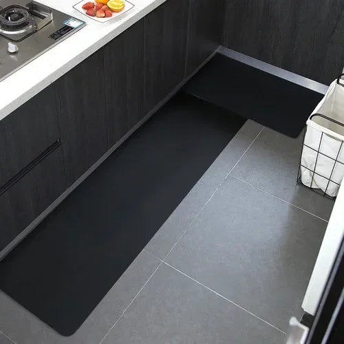 Une cuisine moderne avec des armoires noires et un carrelage gris au sol, offrant un espace de travail fonctionnel et élégant.