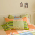 Coussins colorés et rayés sur un lit, donnant une ambiance chaleureuse et accueillante à cette chambre.