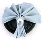 Une boîte ronde noire garnie d'un ruban décoratif bleu clair, avec un ornement argenté au centre.