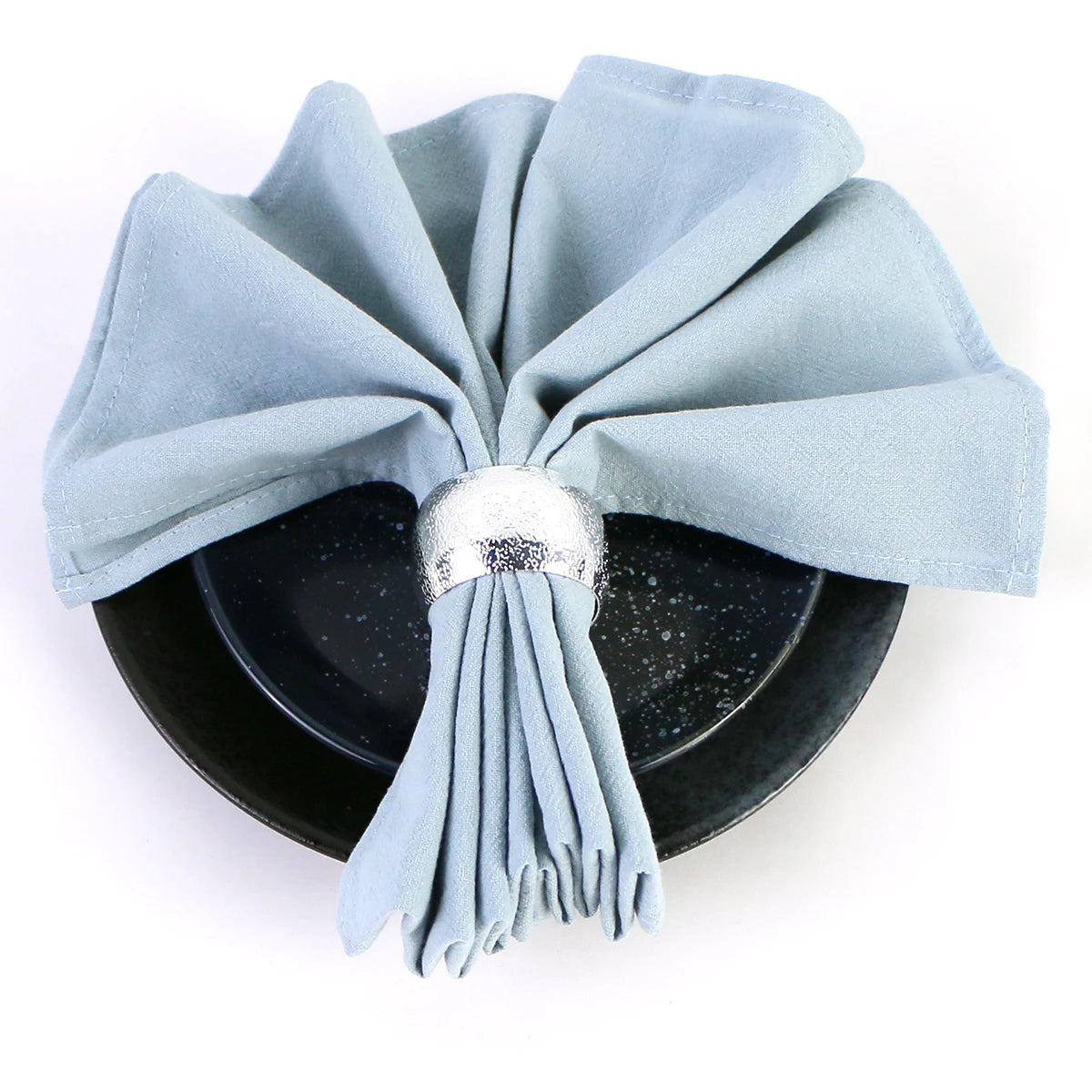 Une boîte ronde noire garnie d'un ruban décoratif bleu clair, avec un ornement argenté au centre.
