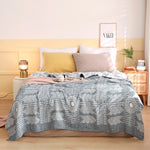 Une chambre à coucher confortable et douillette avec un lit douillet recouvert d'une couverture aux motifs graphiques gris et blancs, des oreillers assortis et une décoration sobre mais élégante.