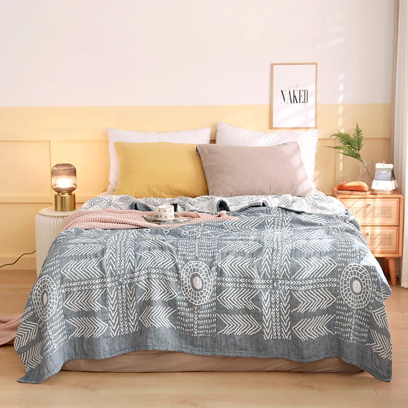 Une chambre à coucher confortable et douillette avec un lit douillet recouvert d'une couverture aux motifs graphiques gris et blancs, des oreillers assortis et une décoration sobre mais élégante.