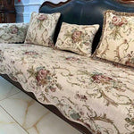 Le canapé à fleurs beige et vintage avec ses coussins ornementés crée une atmosphère cosy et raffinée dans cette pièce.