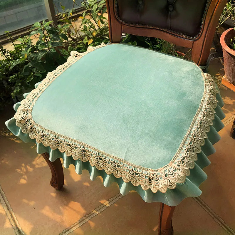 Chaise ancienne tapissée d'un tissu vert pâle avec une dentelle beige ornant le bord.
