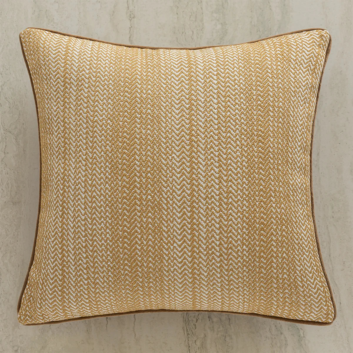 Coussin décoratif en tissu texturé aux motifs dorés et beiges, créant un effet chic et élégant.