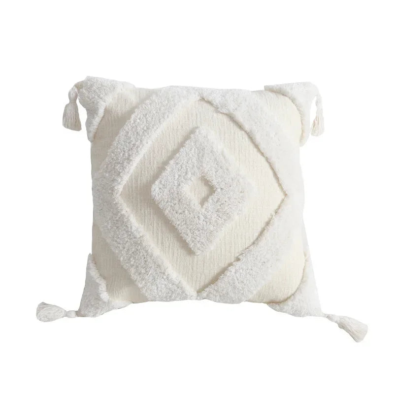 Coussin décoratif moelleux et texturé avec motifs géométriques blancs, orné de franges, parfait pour une déco cocooning et chaleureuse.