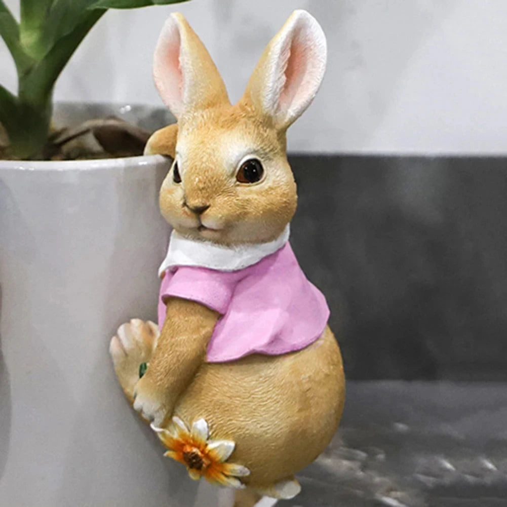Peluche de lapin mignon portant un haut rose, assis dans un pot de fleurs avec une marguerite.