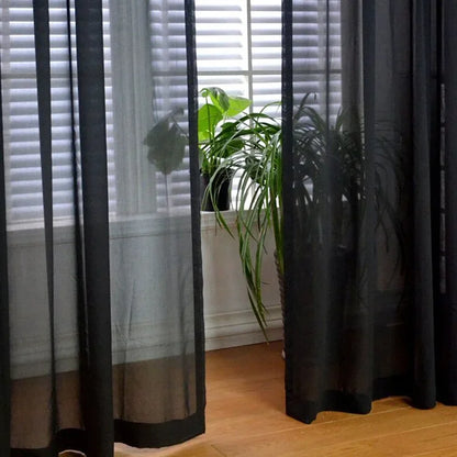 Image d'un rideau élégant et luxueux, en textile riche, de couleur noire, en pleine descente, couvrant une grande fenêtre dans un contexte de design d'intérieur contemporain. Cette image illustre parfaitement l'efficacité et la beauté des traitements de fenêtre, des stores et des rideaux en tant qu'éléments essentiels de la décoration intérieure.